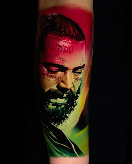 Colorful tattoo of a face with a beard on a person's arm.